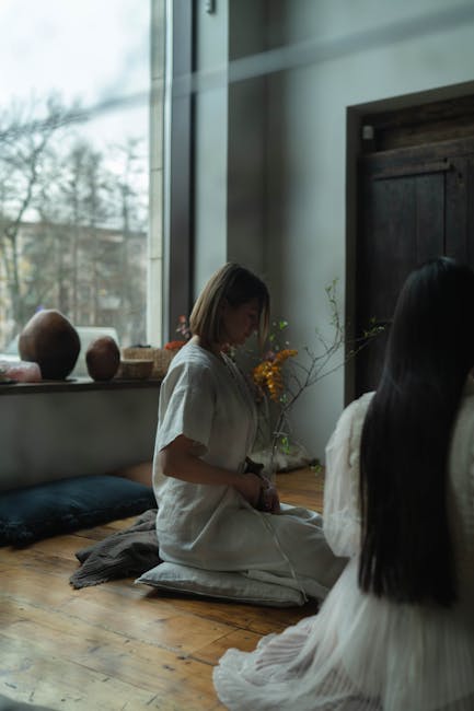 Woman meditating peacefully in a brightly lit space with natural decor.